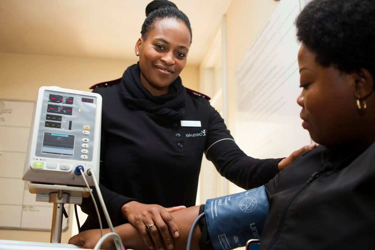 A healthcare professional gently checks a woman’s blood pressure, resting a reassuring hand on her shoulder